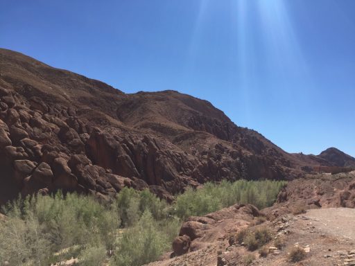 Rocky hills with sparse vegetation under a clear blue sky.